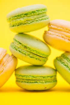 Close up of tasty variation of fresh macaroons on yellow background. Sweet snack