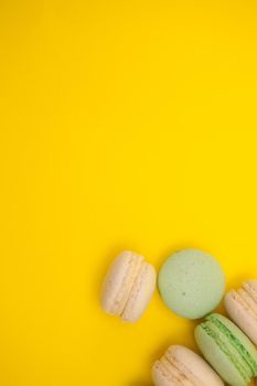 Different types of macaroons over yellow background. Sweet dessert