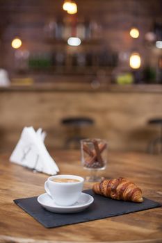 Hot coffee and croissant on coffee shop wooden table. Coffee aroma. Knapkins