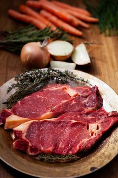 Raw Beef steak and fresh ingredients for cooking on rustic background. Chopped white onion. Fresh carrots. Healthy protein.