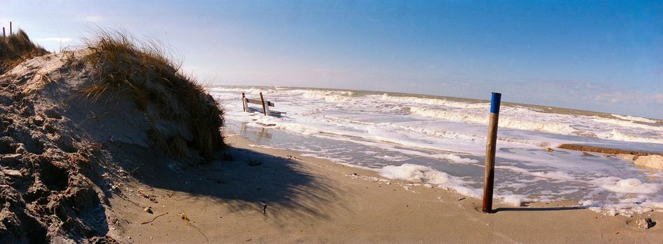panorama of a bench in a rising sea with a sanddune