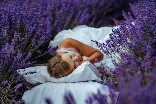 A middle-aged woman lies in a lavender field and enjoys aromatherapy. Aromatherapy concept, lavender oil, photo session in lavender.