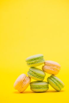 Delicious french macaroon biscuit over yellow background. Delicate dessert