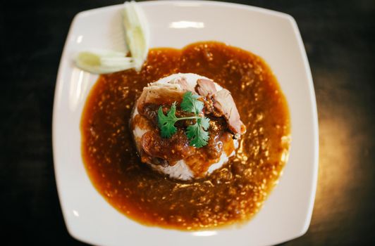 A plate of Chinese BBQ pork on rice with gravy on top.