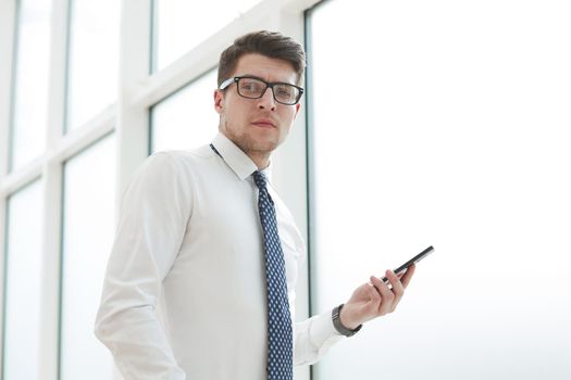 Businessman using smart phone in blurred office space background and copy space