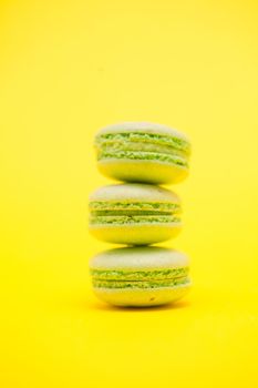 French colorful green macaroons over yellow background. Birthday dessert