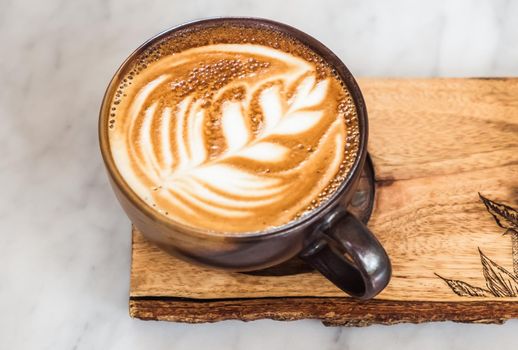 A cup of coffee latte top view with leaf shape foam