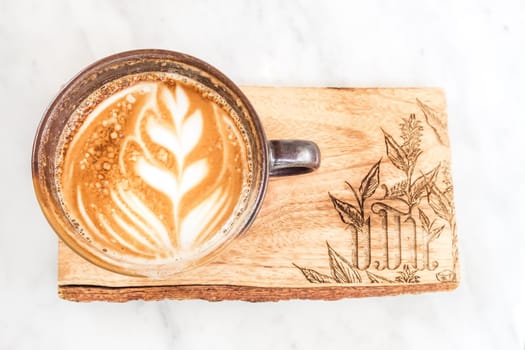 A cup of coffee latte top view with leaf shape foam