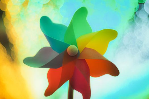 Colorful rainbow pinwheel toy with golden bokeh abstract funny background.