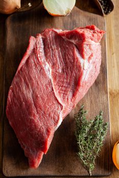 Top view of beefstake seasoned with rosemary on cutting board. White onions.