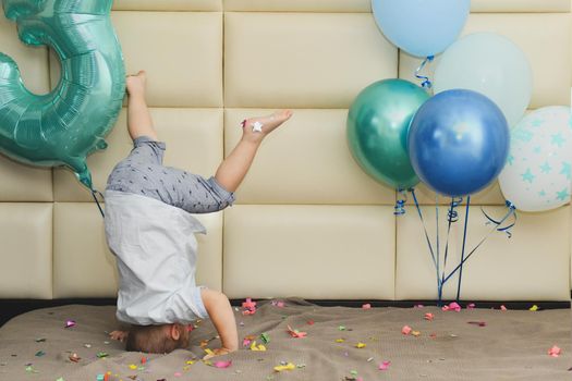 Boy rejoices with confetti and balloons for his birthday Boy upside down for his birthday