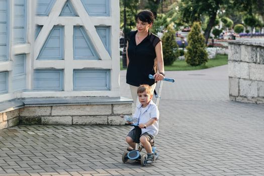 Mother with son support scooters in summer