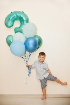 Boy with the number three and the ballons for his birthday at home