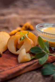 Potato face mask consisting of grated potato and some turmeric powder or haldi in a glass bowl on jute bags surface to brighten the skin, kills bacteria and germs.