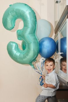 Boy with the number three and the ballons for his birthday at home