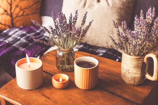 3D render of Autumn hygge home decor arrangement, concept of hygge and coziness, burning white fragrance candle on tray and lavender branches in a bottle vase on table at cozy home