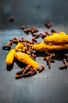 Face mask or pack’s ingredients on wooden surface for acne which are turmeric or haldi and cloves. Ingredients spread on the surface. Vertical shot.