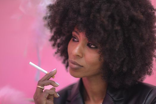 Young attractive African woman with happy cheerful smile smoking in studio