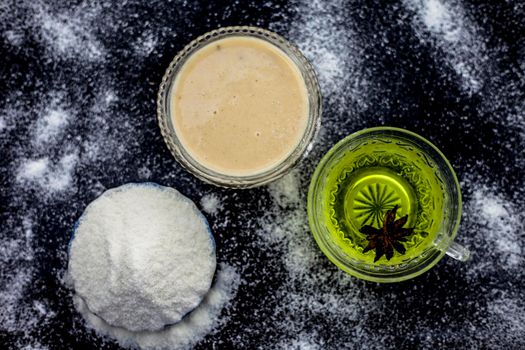 Rice flour and rice grain on wooden surface along with some green tea in a transparent glass cup and a star anise in it.Face mask for the treatment for smoother skin.