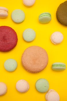 Delicious big caramel macaroon flavour next to cherry macaroon over yellow background. Luxury dessert