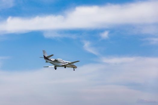 Landing airplane. Landscape with passenger airplane is flying in the blue sky with clouds. Passenger airliner. Business trip. Commercial aircraft. Passenger airplane flying and getting ready to land.