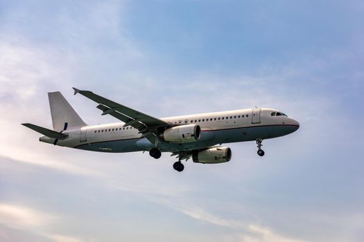 Landing airplane. Landscape with passenger airplane is flying in the blue sky with clouds. Passenger airliner. Business trip. Commercial aircraft. Passenger airplane flying and getting ready to land.
