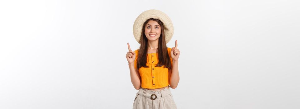 Teenager girl on summer vacation surprised and pointing finger on copy space over isolated white background