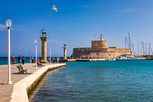 Mandraki port with deers statue, where The Colossus was standing and fort of St. Nicholas. Rhodes, Greece. Hirschkuh statue in the place of the Colossus of Rhodes, Rhodes, Greece