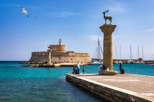 Mandraki port with deers statue, where The Colossus was standing and fort of St. Nicholas. Rhodes, Greece. Hirschkuh statue in the place of the Colossus of Rhodes, Rhodes, Greece