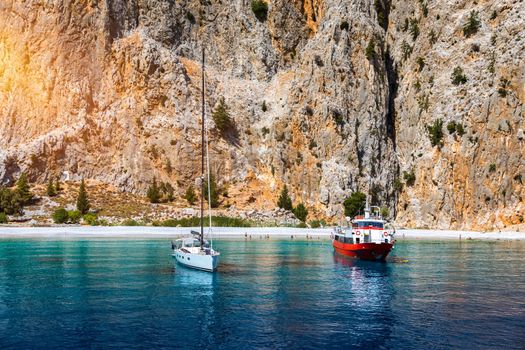 Saint George bay on Symi island, popular stop over for tourists to have a swim in the turquoise waters, Symi island, Greece. Boat sailing at the Symi island and part of the Dodecanese island group.