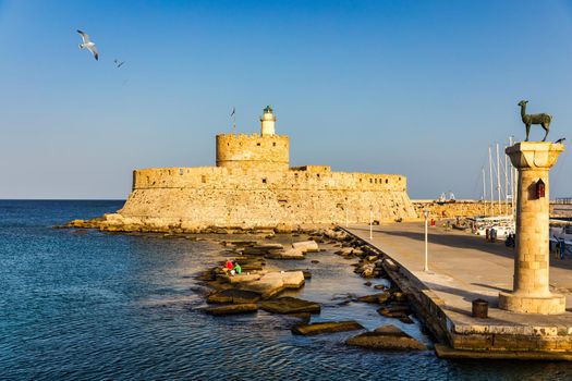 Mandraki port with deers statue, where The Colossus was standing and fort of St. Nicholas. Rhodes, Greece. Hirschkuh statue in the place of the Colossus of Rhodes, Rhodes, Greece