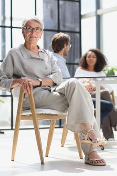 mature woman sitting with laptop looking at camera.