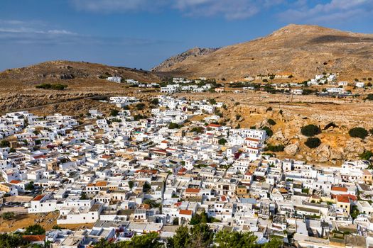 The famous and historical medieval village of Lindos on the Greek island of Rhodes with the Acropolis in the background. Lindos, Rhodes, Greece.