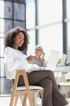 young attractive african american woman in the office sitting at a laptop