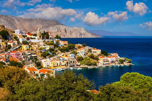 View on Symi (Simi) island harbor port, classical ship yachts, houses on island hills, Aegean Sea bay. Greece islands holidays vacation travel tours from Rhodos island. Symi, Greece,  Dodecanese.