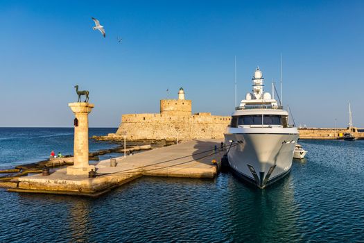 Mandraki port with deers statue, where The Colossus was standing and fort of St. Nicholas. Rhodes, Greece. Hirschkuh statue in the place of the Colossus of Rhodes, Rhodes, Greece