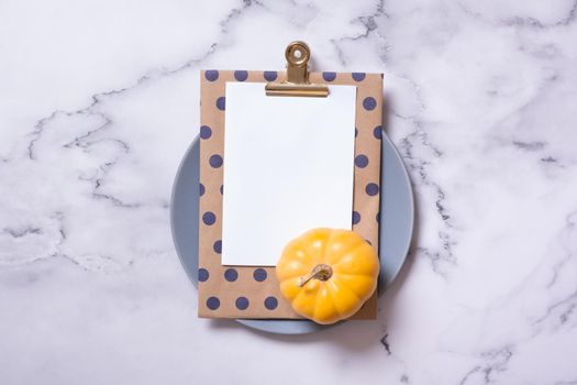 Autumn flat lay with blank tablet and decorative pumpkinon marble background top view.