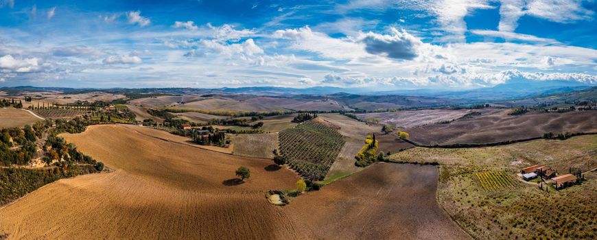 Well known Tuscany landscape with grain fields, cypress trees and houses on the hills at sunset. Summer rural landscape with curved road in Tuscany, Italy, Europe