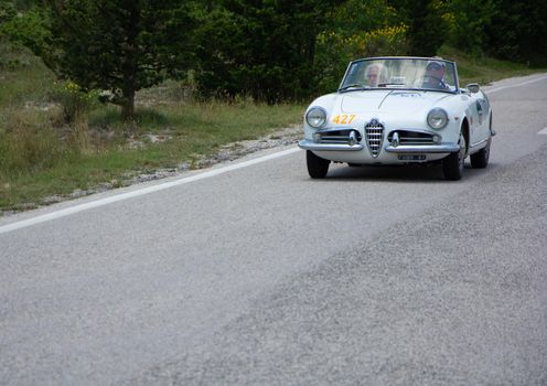 URBINO - ITALY - JUN 16 - 2022 : ALFA ROMEO GIULIETTA SPIDER 1957 on an old racing car in rally Mille Miglia 2022 the famous italian historical race (1927-1957