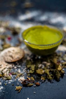 Neem or Indian Lilac face mask on the black wooden surface for acne and scars consisting of gram flour, neem paste, and some curd.