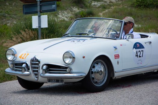 URBINO - ITALY - JUN 16 - 2022 : ALFA ROMEO GIULIETTA SPIDER 1957 on an old racing car in rally Mille Miglia 2022 the famous italian historical race (1927-1957