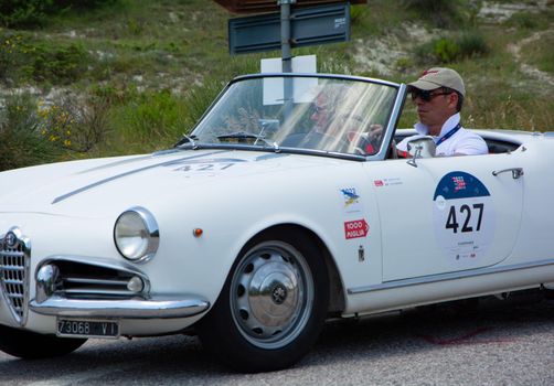 URBINO - ITALY - JUN 16 - 2022 : ALFA ROMEO GIULIETTA SPIDER 1957 on an old racing car in rally Mille Miglia 2022 the famous italian historical race (1927-1957