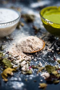 Neem or Indian Lilac face mask on the black wooden surface for acne and scars consisting of gram flour, neem paste, and some curd.