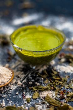 Neem or Indian Lilac face mask on the black wooden surface for acne and scars consisting of gram flour, neem paste, and some curd.