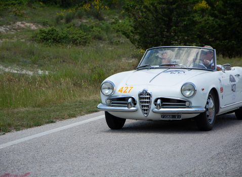 URBINO - ITALY - JUN 16 - 2022 : ALFA ROMEO GIULIETTA SPIDER 1957 on an old racing car in rally Mille Miglia 2022 the famous italian historical race (1927-1957