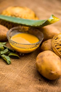 Homemade conditioner and shampoo for dandruff and scalp cleaning on jute bag's surface i.e. potato juice well mixed with aloe vera gel in a glass bowl along with raw potato and some aloe vera leaf.