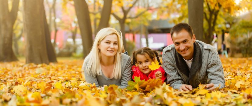 Happy family is sitting in beautiful autumn park