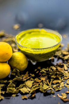 Neem or Indian Lilac face mask on the black wooden surface for oily skin consisting of neem leaves paste and lemon juice well mixed with rose water.