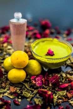 Neem or Indian Lilac face mask on the black wooden surface for oily skin consisting of neem leaves paste and lemon juice well mixed with rose water.