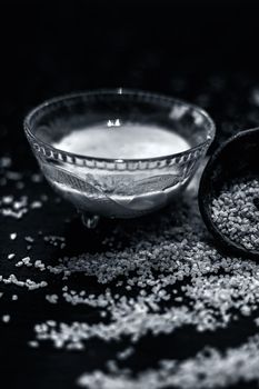 Curd or yogurt and oats face mask on the woodne surface in a glass bowl along with some raw oats in a black colored clay bowl and some spread on the surface. To Exfoliate Your Skin.